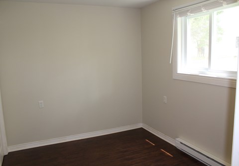 A room with a window and wooden floors.